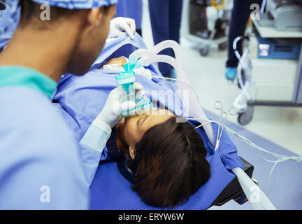 Anesthesiologist holding oxygen mask over patient’s face in operating room Stock Photo