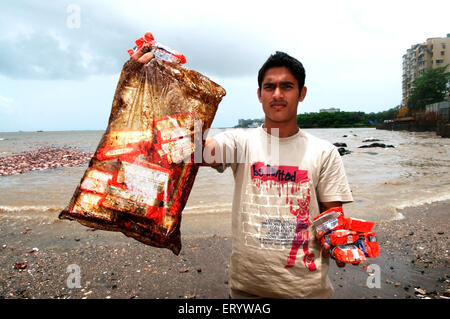 Man showing oil soaked biscuit packets due to oil spill of container ship chitra colliding in sea Bombay Mumbai Maharashtra India - aum 175662 Stock Photo