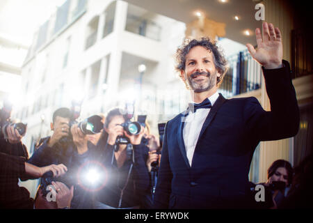 Celebrity waving to paparazzi photographers at event Stock Photo