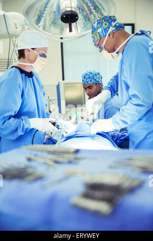 Surgeons performing surgery in operating room Stock Photo