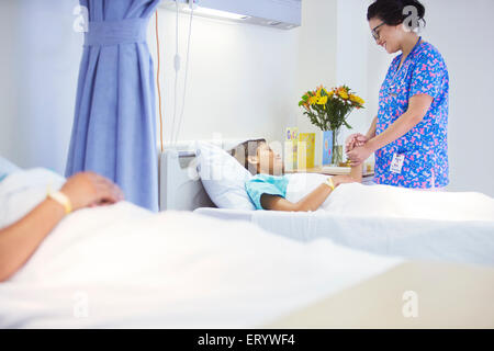 Nurse holding hands with patient in hospital room Stock Photo