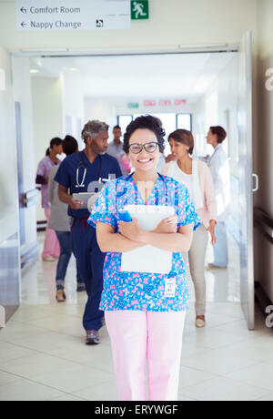 Portrait of confident nurse with clipboard in hospital corridor Stock Photo