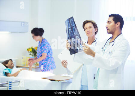 Doctors reviewing MRI scans in hospital room Stock Photo
