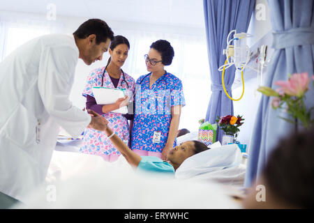 Doctor and nurses making rounds in hospital room Stock Photo