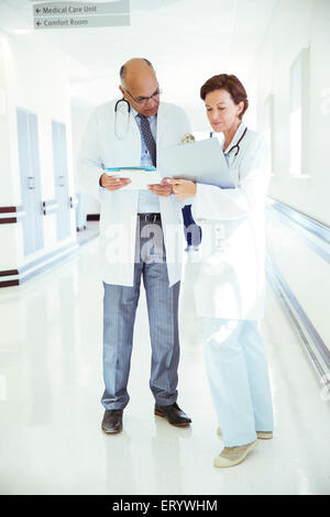 Doctors with medical charts consulting in hospital corridor Stock Photo