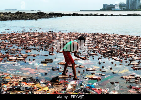 Boy searching biscuit packets from oil soaked  due to container ship chitra colliding in sea Bombay Mumbai Stock Photo
