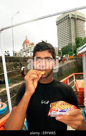 Man eating oil soaked biscuit packets due to container ship chitra colliding in sea Bombay Mumbai ; Maharashtra ; India NOMR Stock Photo