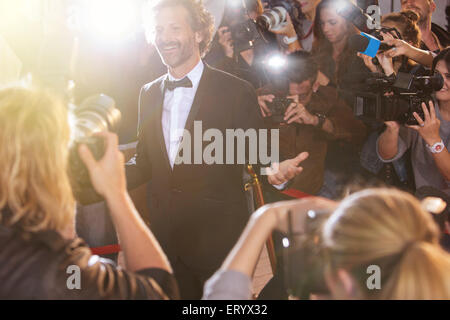 Smiling celebrity posing for paparazzi photographers at event Stock Photo
