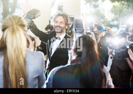 Celebrity waving at paparazzi photographers at event Stock Photo