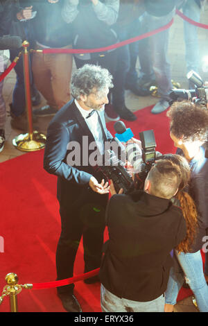Celebrity being interviewed and photographed by paparazzi photographers at red carpet event Stock Photo