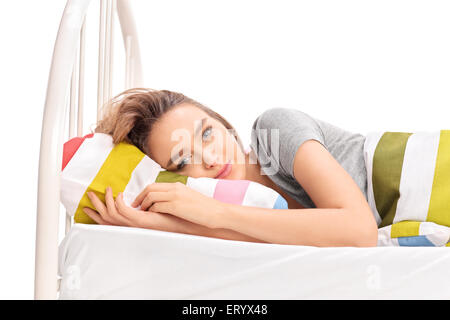 Gorgeous brunette woman lying in a comfortable bed and looking at the camera isolated on white background Stock Photo