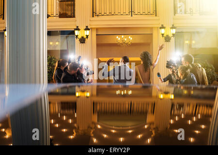 Celebrity couple arriving and waving at paparazzi photographers at event Stock Photo