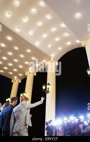 Celebrities waving at paparazzi photographers at event Stock Photo