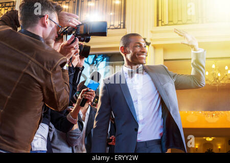 Celebrity waving and being photographed by paparazzi photographers Stock Photo