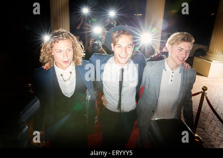 Smiling celebrities walking in a row at red carpet event Stock Photo