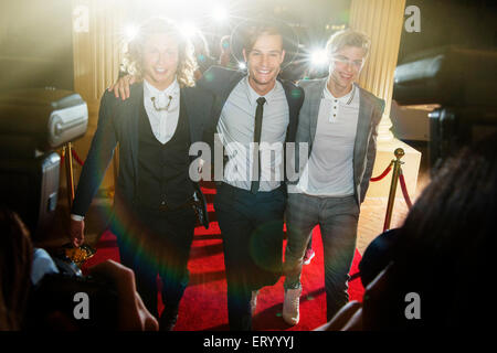 Portrait of smiling celebrities in a row arriving at red carpet event Stock Photo