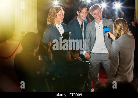 Smiling celebrities being interviewed at event Stock Photo