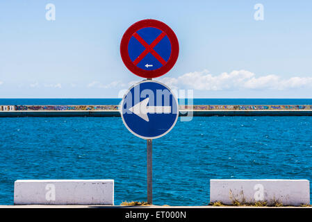 No parking sign and another sign of compulsory direction with the sea and sky background Stock Photo