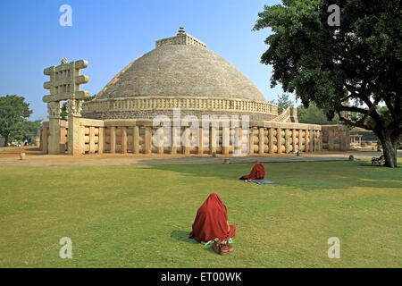 Buddhist monk reading scriptures in front of Stupa 1 constructed by king Ashok ; Sanchi  ; Madhya Pradesh ; India Stock Photo