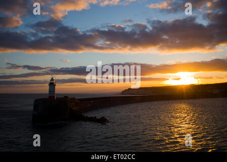 Sunset behind cliffs and lighthouse, harbour wall, Newhaven, Sussex, UK Stock Photo