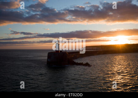 Sunset behind cliffs and lighthouse, harbour wall, Newhaven, Sussex, UK Stock Photo