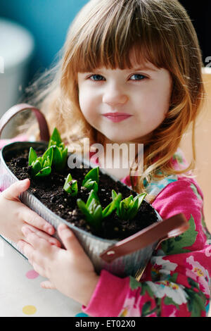Close up portrait of girl holding sprouting flowers in basket Stock Photo