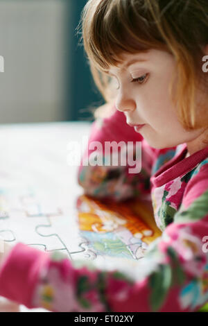 Close up of serious girl assembling jigsaw puzzle Stock Photo