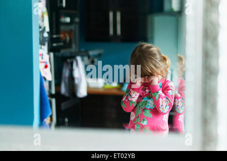 Reflection of upset girl rubbing eyes in mirror Stock Photo