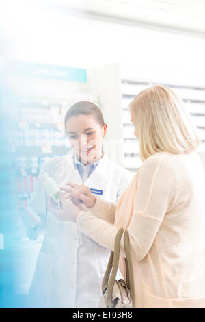 Pharmacist and customer reviewing label on bottle in pharmacy Stock Photo