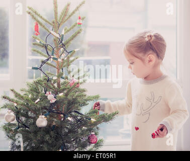 Girl decorating small Christmas tree Stock Photo