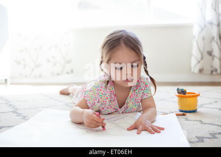 Girl on floor drawing with crayons Stock Photo