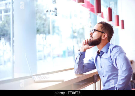 Pensive businessman at laptop in cafe Stock Photo