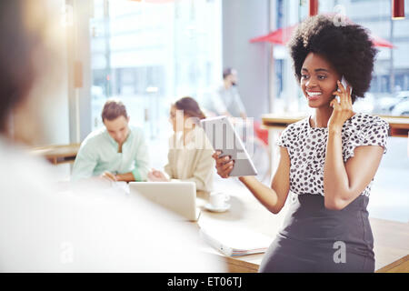 Businesswoman talking and cell phone and using digital tablet Stock Photo