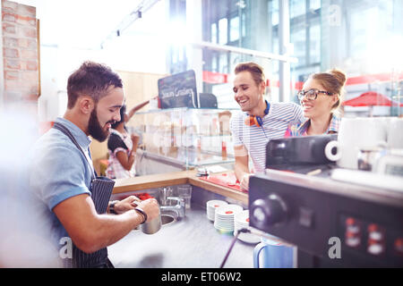 Customers watching barista make coffee in cafe Stock Photo