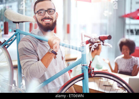 Smiling man carrying bicycle in cafe