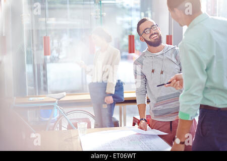 Smiling architects talking and reviewing blueprints Stock Photo