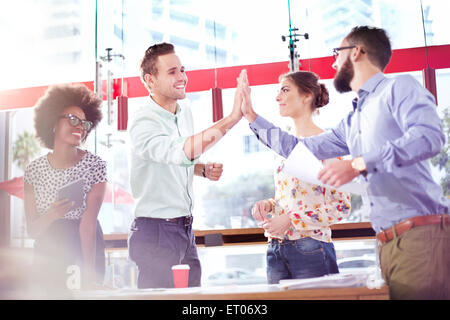 Business people high fiving in meeting Stock Photo