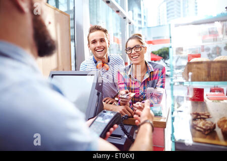 Smiling couple paying worker at cafe counter Stock Photo