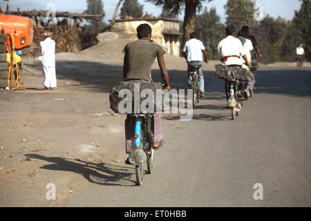 Workers from coal mine carrying lump of coal loaded back seat of bicycles in Jharkhand ; India Stock Photo