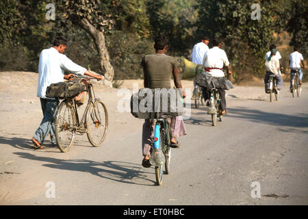 Workers from coal mine carrying lump of coal loaded back seat of bicycles in Jharkhand ; India Stock Photo