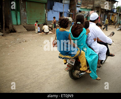 A family of five members riding on a motorbike in the textile town of Malegaon ; Maharashtra ; India Stock Photo