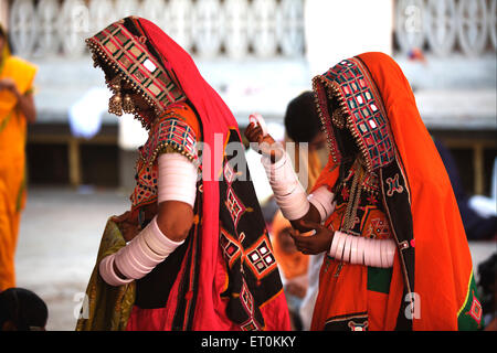 Nomad women dressed in their traditional colourful attire sitting outside the Sachkhand Saheb Gurudwara in Nanded Stock Photo