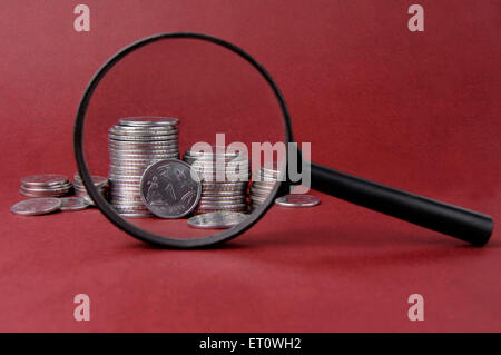 Magnifying glass and coins Stock Photo