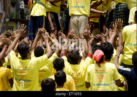 Helping hands to support human pyramid trying to break dahi handi on janmashtami festival at dadar Mumbai Stock Photo