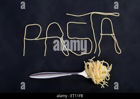 Word pasta made of cooked spaghetti with fork with rolled spaghetti on it in black background Stock Photo
