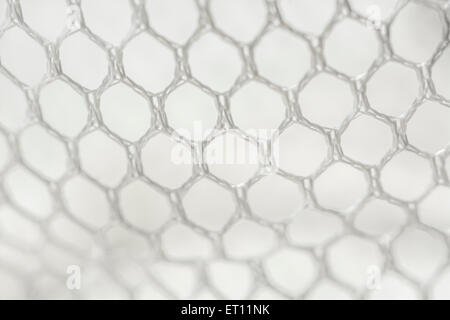 Macro-photo of fine white woven polyester mesh / netting against off-white background. Holes approx. 4mm in diameter. Stock Photo