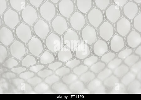 Macro-photo of fine white woven polyester mesh / netting against off-white background. Holes approx. 4mm in diameter. Stock Photo