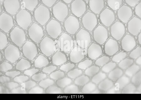 Macro-photo of fine white woven polyester mesh / netting against off-white background. Holes approx. 4mm in diameter. Stock Photo