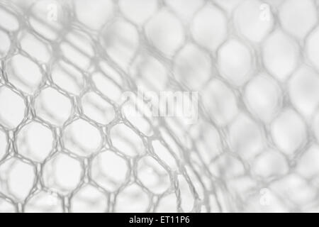 Macro-photo of fine white woven polyester mesh / netting against off-white background. Holes approx. 4mm in diameter. Stock Photo