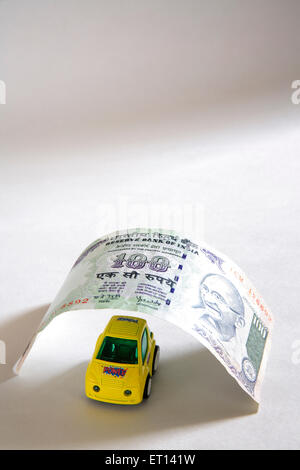 Car loan concept , plastic yellow car model below one hundred rupee on white background Stock Photo